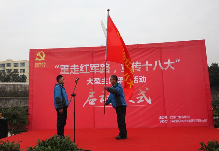 旗手庄重地从陈部长手中接过鲜红的旗帜.