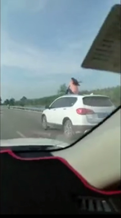 实拍:女子公路上坐车顶"自由飞翔"