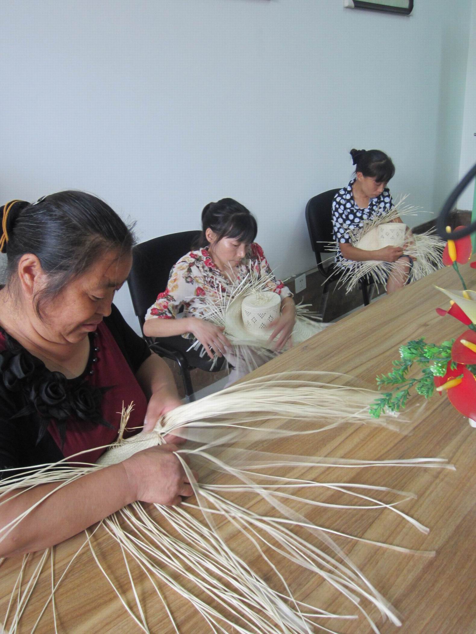 就业培训中心内,残疾人正在进行棕编技能交流