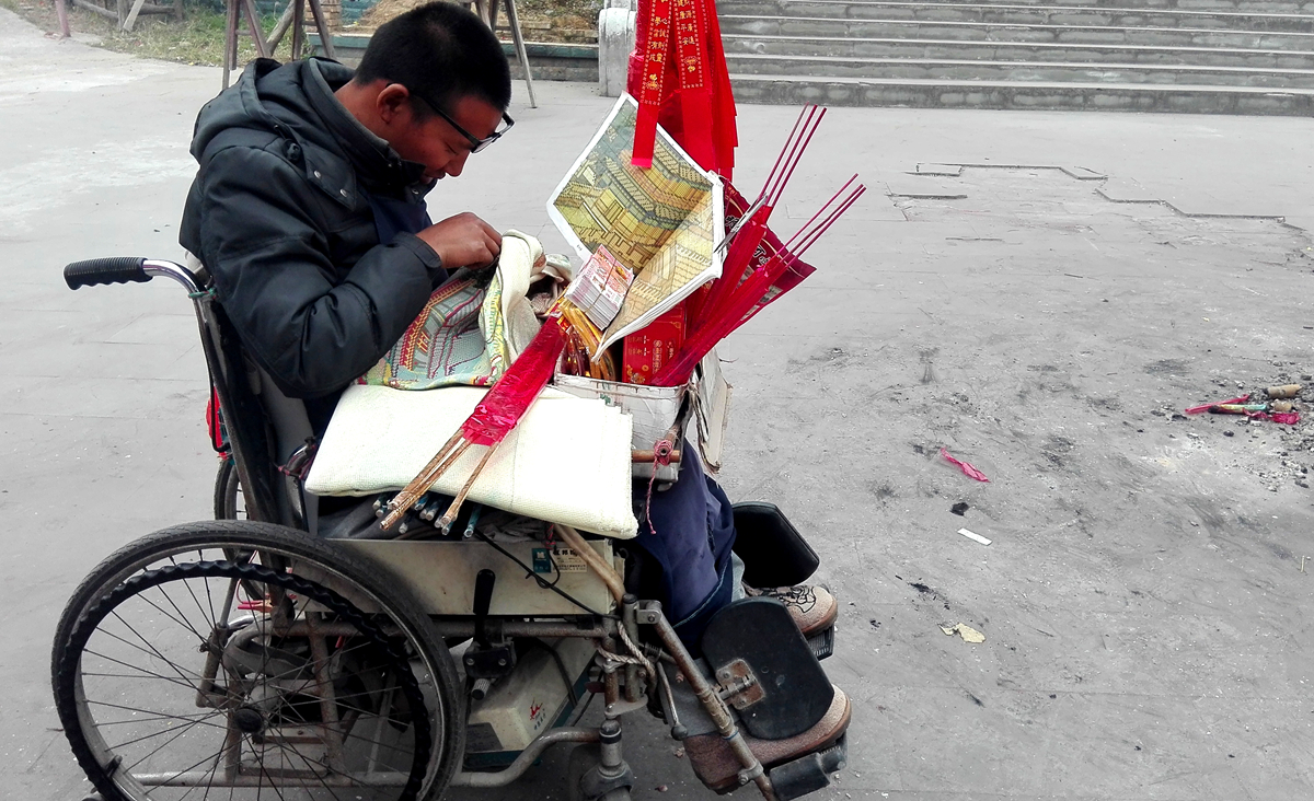 这位轮椅小哥常年在这里卖香蜡纸烛,正在埋首苦绣《清明上河图》